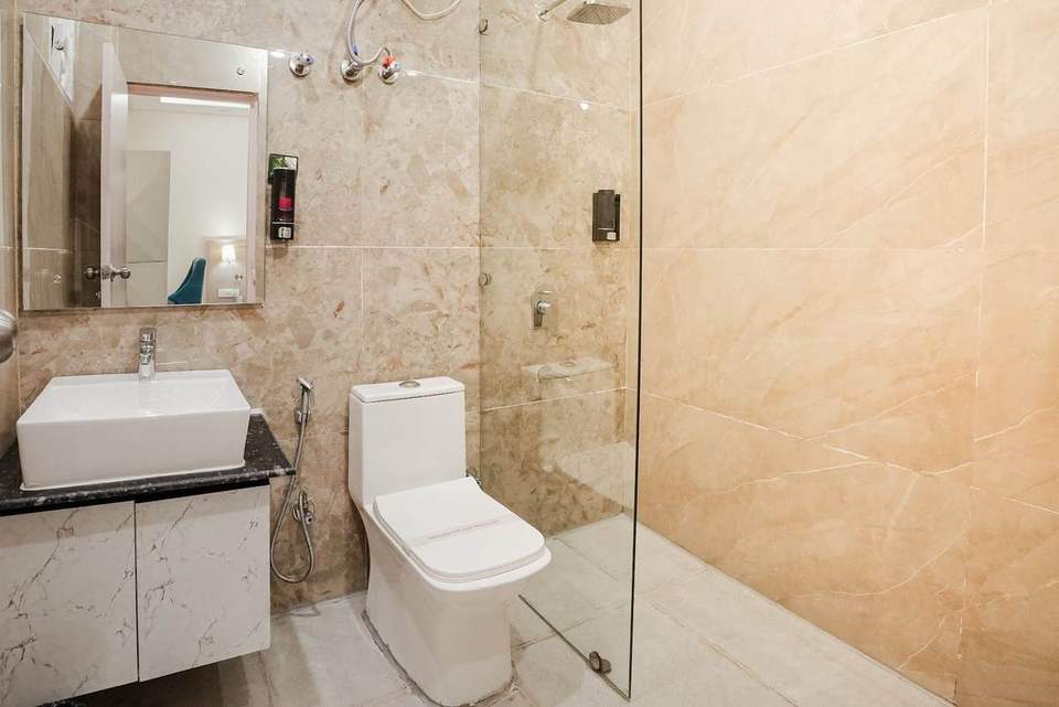 Clean attached bathroom with marble-look tiles, glass shower and vessel sink at Alpine Retreat, Rishikesh