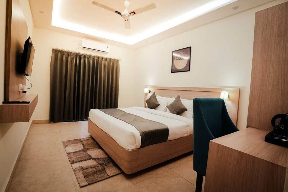 Deluxe Room with king bed, teal chair, work desk and dark curtains at Alpine Retreat, Rishikesh