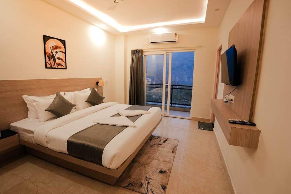 Deluxe Room with king bed, TV and glass door to a private balcony over the valley at Alpine Retreat, Rishikesh