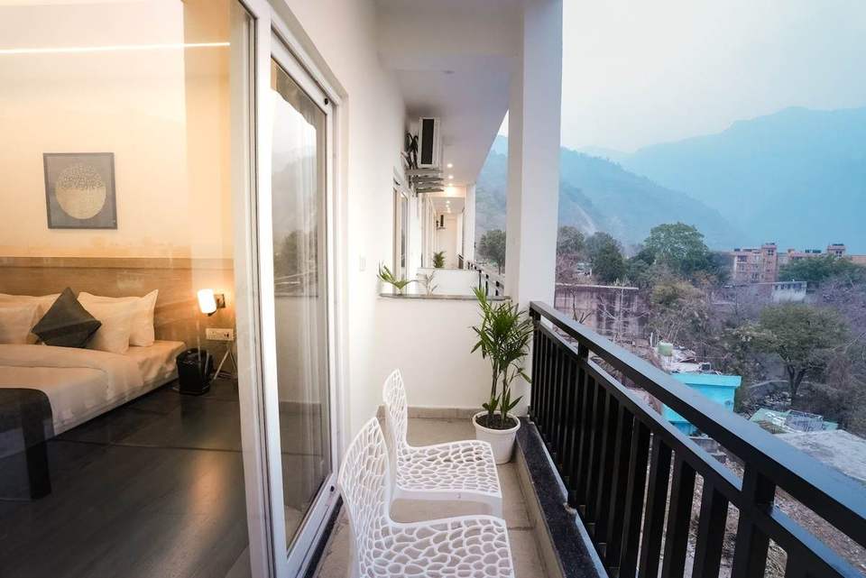 Private balcony with white chairs next to a Deluxe Room, overlooking the valley in Tapovan, Rishikesh