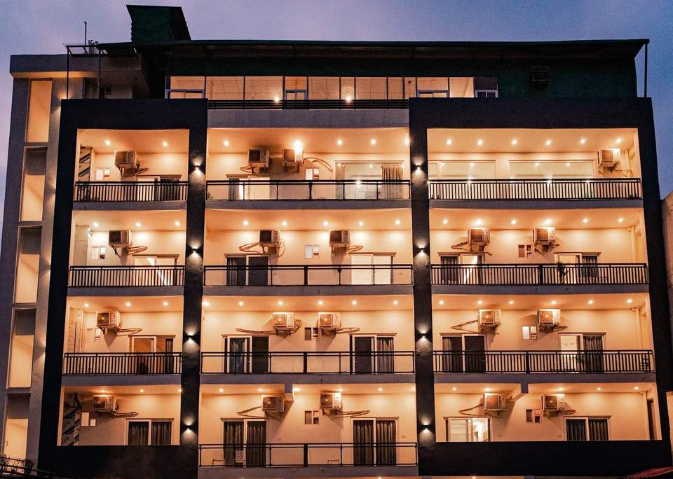 Alpine Retreat hotel facade lit up at dusk with warm lights on every balcony, Tapovan, Rishikesh