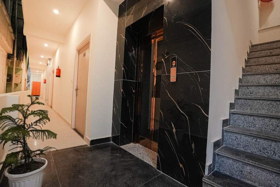 Corridor with a lift, potted plant and room doors at Alpine Retreat hotel in Tapovan, Rishikesh