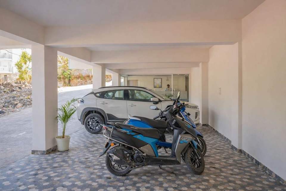 Covered parking with a car and scooter at the ground floor of Alpine Retreat hotel, Tapovan, Rishikesh