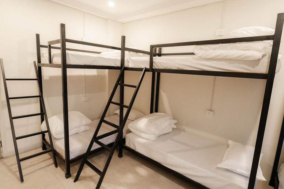 Six black metal bunk beds with white linen in the dormitory at Alpine Retreat, Tapovan, Rishikesh