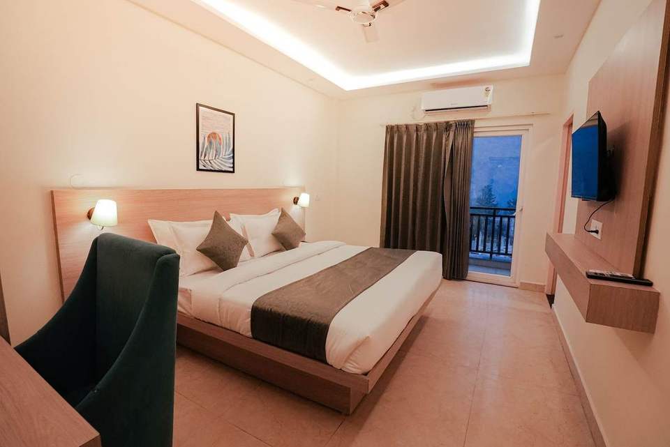 Standard Room with king bed, velvet armchair and balcony door at Alpine Retreat, Rishikesh