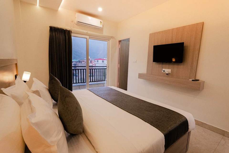 Standard Room with king bed and a glass door to a balcony overlooking the hills at Alpine Retreat, Rishikesh