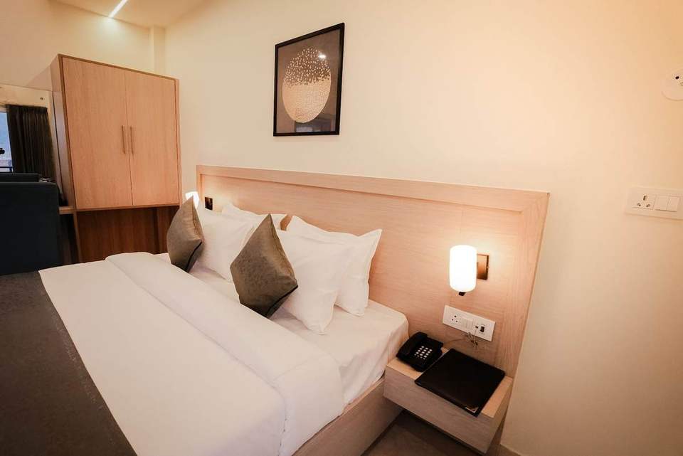Standard Room bed with cushions, wall lamp and bedside phone at Alpine Retreat, Rishikesh