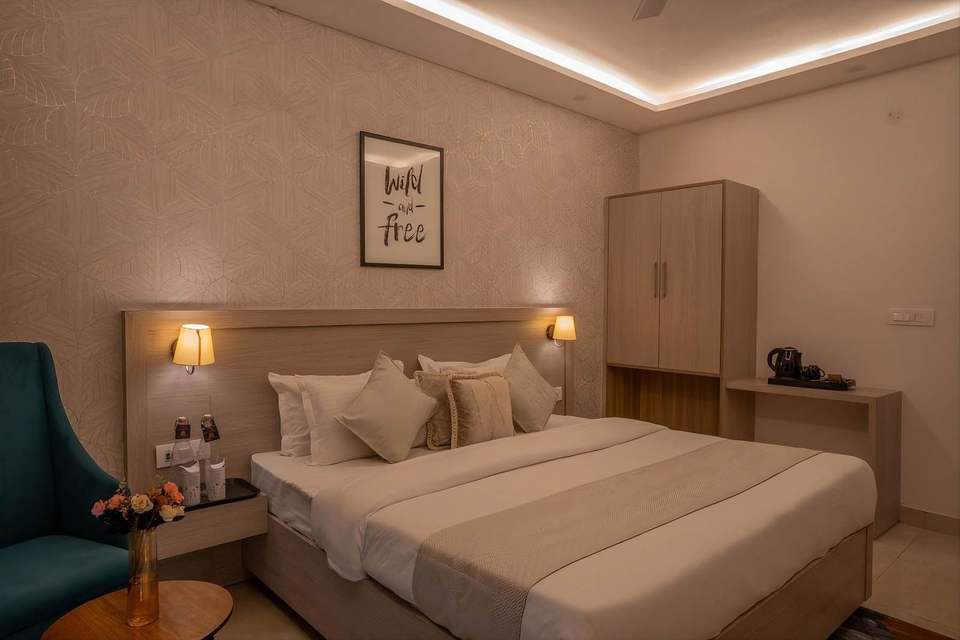 Super Deluxe Room with king bed, teal armchair and fresh flowers at Alpine Retreat, Rishikesh