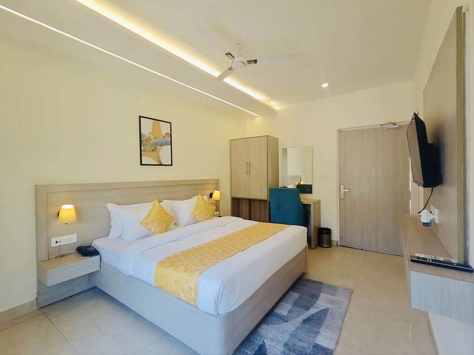 Spacious Super Deluxe Room with king bed, yellow cushions and work desk at Alpine Retreat, Rishikesh
